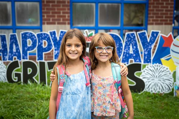 two girls in front of happy first day grizzlies sign